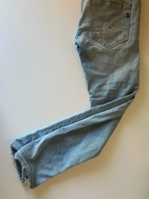 Ljusblå raka jeans med rå kant - Säljer ett par ljusblå jeans med rak passform och rå, fransig kant vid bensluten. Jeansen har klassiska bakfickor och är tillverkade i mjukt denimtyg. Perfekta för en avslappnad och trendig look.