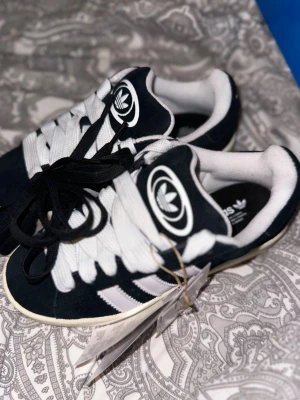 Adidas campus  - Säljer ett par klassiska Adidas sneakers i svart och vitt med gummisula och snörning.  Adidas campus, kommer med svarta snören också. HELT NYA MED KARTON OCH PRISLAPP