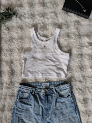 Vit ribbad croppad linnetopp - Snygg vit croppad linnetopp från Lager157 i ribbat bomullsmaterial. Toppen är ärmlös med breda axelband och har en enkel, stilren design som passar perfekt till jeans eller kjol.
