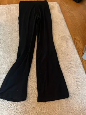 Svarta utsvängda leggings - Snygga svarta leggings med utsvängda ben och hög midja. Mjukt och stretchigt material som sitter bekvämt och följer kroppen. Perfekta för en trendig och avslappnad stil.