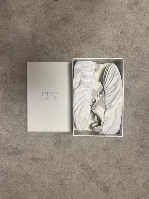 Vita och beige sneakers i mocka och skinn - Snygga sneakers i vitt och beige med paneler i mocka och släta partier i skinn. Klassisk låg modell med vita skosnören och diskret design. Perfekta för dig som gillar stilrena och trendiga skor.