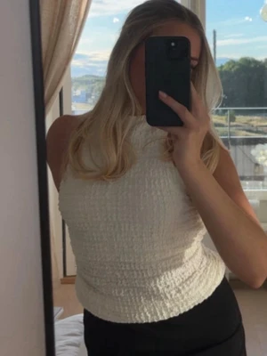 Halterneck topp från Zara - Säljer en snygg vit topp från Zara som är superfin i ryggen. Toppen är hög i halsen och har en strukturerad, lite skrynklig yta. Använd någon enstaka gång. Storlek M men passar mig som har S i vanliga fall 🩷