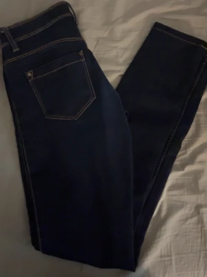 Mörkblå skinny jeans från ONLY - Snygga mörkblå skinny jeans från ONLY med klassiska kontrastsömmar och femficksmodell. Jeansen har normal midja och är tillverkade i stretchigt material för en bekväm passform. Perfekta till vardagslooken och lätta att matcha med olika stilar.