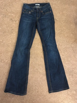 Mörkblå bootcut jeans från Perfect Jeans - Snygga mörkblå bootcut jeans från Perfect Jeans med klassiska kontrastsömmar och fem fickor. Jeansen har en något utsvängd passform nedtill och är tillverkade i slitstark denim. Perfekta för dig som gillar en tidlös look.