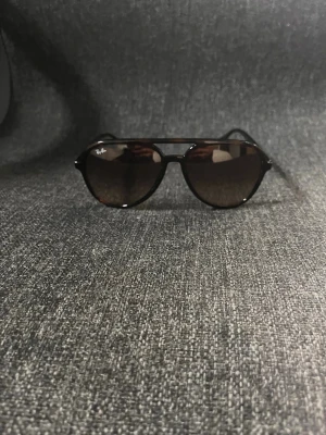 Ray-Ban bruna pilotbågar solglasögon - Snygga solglasögon från Ray-Ban med klassisk pilotform och bruna bågar. Glasen är mörka och ger en cool look. Perfekta för soliga dagar och ger en tidlös vibe till din outfit.