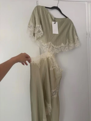 Ljusbeige långklänning med spets - Säljer denna helt slutsålda klänning från Zara. Aldrig använd! Klänningen har korta ärmar, cut out-detaljer i midjan och slits framtill. 