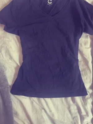 Mörkblå v-ringad t-shirt - En enkel och stilren mörkblå t-shirt med v-ringning och korta ärmar. Tillverkad i mjuk bomull som känns skön mot huden. Perfekt basplagg till garderoben och lätt att matcha med olika outfits.