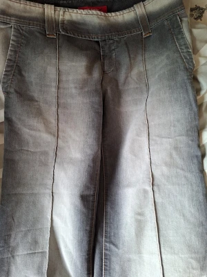 Grå jeans från Miss Sixty - Säljer ett par grå jeans från Miss Sixty med raka ben och markerade pressveck framtill. Jeansen har breda hällor för bälte och klassisk femficksdesign. Materialet är denim med en tvättad look som ger en cool vintagekänsla.