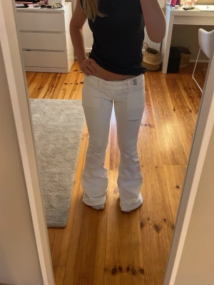 Vita bootcut jeans från gina - Säljer ett par vita  helt oanvända bootcut jeans med låg midja och snygg brodyr på bakfickorna. Jeansen har fickor fram och bak samt hål på knäna och ett litet på låret. Säljer de här fina jeansen eftersom de var för stora när jag köpte de. Det är från gina 14+ och är i strl S🌸💕