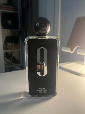 Afnan 9PM edp 100ml - Afnan 9PM Eau de Parfum är en parfym i en stilren, rektangulär glasflaska med svart etikett och stor silverfärgad siffra 9. Flaskan har en rund, mörk kork och rymmer 100 ml. Doften är känd för sina intensiva och moderna noter. In princip helt full