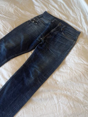 Mörk blå jeans med paint splater och patch - Mått: Midja 41cm Lår 26cm Benöppning 17cm Längs 103cm Några undringar är det bara att fråga.