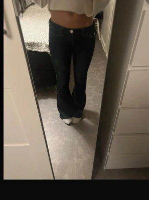 true religion jeans - Säljer ett par mörkblå bootcut jeans från True Religion med klassiska kontrastsömmar och dekorativa ficklock bak. Jeansen har låga midja och vanlig längd har bara syt ner så att dom blir extra låga än vad dom redan är kan sänka max till 600-700 har bara använt dom en gång 