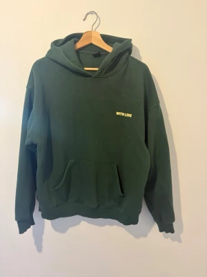 Mörkgrön hoodie med tryck - Säljer en mörkgrön hoodie med luva.