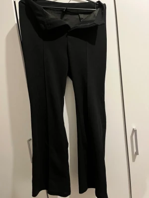 Svarta bootcut leggings - Säljer ett par svarta leggings med bootcut-modell och hög midja. De har en enkel design utan synliga detaljer och är tillverkade i ett stretchigt material som sitter bekvämt. Perfekta för en avslappnad och trendig look.
