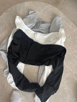 3-pack boleros - Säljer ett set med tre boleros i svart, vit och ljusgrå. Alla topparna har en enkel, stilren design och är perfekta att matcha till olika outfits. Materialet känns mjukt och stretchigt, vilket gör dem bekväma att bära hela dagen.