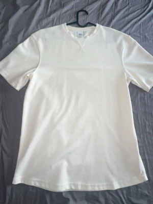 Zara T-shirts  - Klassisk vit t-shirt från Zara med rund halsringning och korta ärmar. Tillverkad i mjuk bomull med diskret struktur i tyget. Enkel och stilren modell som passar till det mesta.