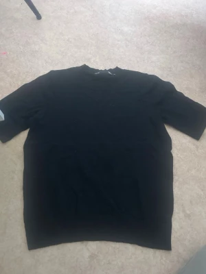 Svart basic t-shirt med kort ärm - En enkel svart t-shirt med klassisk rund hals och korta ärmar. Perfekt till alla outfits och lätt att matcha med andra plagg. Tillverkad i mjukt material som känns skönt mot huden.
