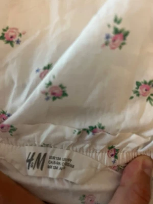 Vit blommig offshoulder blus H&M - Söt vit blus från H&M med små blommiga mönster i rosa och grönt. Modellen är offshoulder med korta ärmar och har en luftig, loose passform. Använd 1 gång.