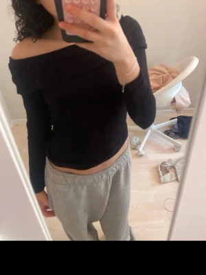 Svart offshoulder topp - Säljer en svart offshoulder topp med lång ärm. Toppen har en tight passform och sitter snyggt över axlarna. Perfekt att styla med både jeans och kjol för en trendig look.