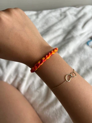 Flätat armband i rött och gult - Ett handgjort armband i flätad design med röda och gula trådar. Armbandet justerbar enkelt runt handleden och ger en färgglad och lekfull touch till din stil. Perfekt för dig som gillar unika accessoarer och vill sticka ut lite extra.💕