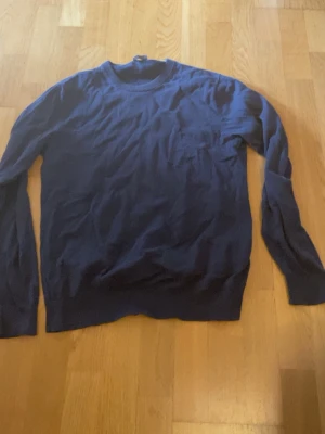 Mörkblå stickad tröja unisex - En enkel och stilren mörkblå stickad tröja  med rund halsringning och långa ärmar. Tröjans storlek är xs har en liten defekt på ena axeln men inget som syns 