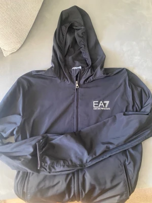 Vind jacka EA7 Emporio Armani svart  - Vind jacka EA7 Emporio Armani svart. Storlek L men känns som en M. 