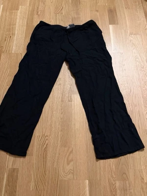 Svarta linnebyxor från H&M - Svarta linnebyxor från H&M med raka ben och dragsko i midjan. Materialet är en skön mix av viskos och linne som ger en avslappnad känsla. Perfekta för dig som gillar enkel och clean stil. Tyvärr ganska små i storlek och korta pga av dålig tidigare tvätt. Köpta för flera år sedan på hm.             Katt finns i hemmet!