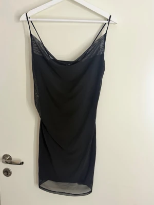 Svart klänning  - Svart kort klänning från H&M med tunna axelband och meshdetaljer. Klänningen har passform och är perfekt för dig som gillar en enkel men snygg stil. Materialet är lätt och luftigt.