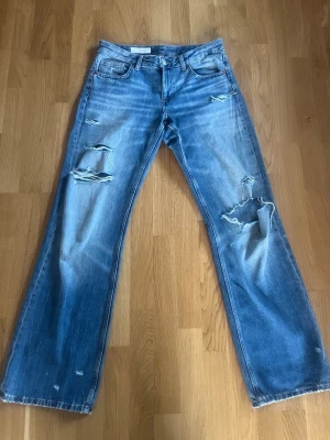 Blå slitna raka jeans - Blå raka Zara jeans med slitningar. Innerbenslängden är 83 cm ochmidjemåttet är 39 cm. Jag är 178 cm lång och de går ner till marken på mig. Hör av dig vid frågor💕Finns en defekt vilket är att slitningen på knät har spruckit något.