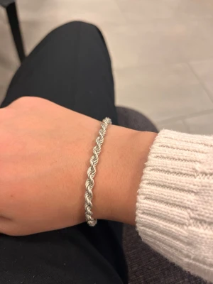 925 silver Cordell 5mm armband - Snyggt armband med flätad design i silverfärg. Armbandet har en klassisk karbinlås och passar perfekt för dig som gillar stilrena accessoarer. Materialet är 925 sterling silver och det är lätt att bära till olika outfits. Måttet är 18,5 cm lång och är 5mm tjock.