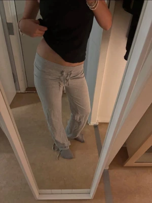 Gråa mjukisbyxor med dragsko - Säljer ett par gråa mjukisbyxor med bred mudd i midjan och dragsko framtill. Byxorna har raka ben och är tillverkade i ett mjukt och stretchigt material som passar perfekt för chill dagar. Klassisk och enkel design utan synligt märke.