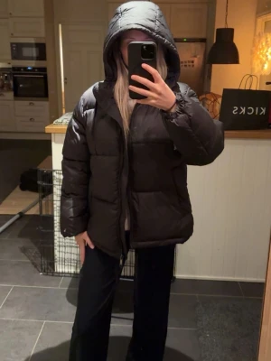 Svart pufferjacka med huva - Säljer en svart pufferjacka med stor huva och quiltad design. Jackan är oversized. ( OBS lånade bilder från hon jag köpte jackan från💕) jackan är i fink skicka och är lite större i storleken men passar mig bra, kommer ej till andvändning ☺️