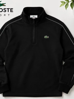 Äckta Svart half-zip tröja från Lacoste - Snygg svart half-zip tröja från Lacoste Sport med vit piping längs axlarna och det klassiska gröna krokodilmärket på bröstet. Tröjan har hög krage och ribbade muddar. Perfekt för en sportig och clean look.