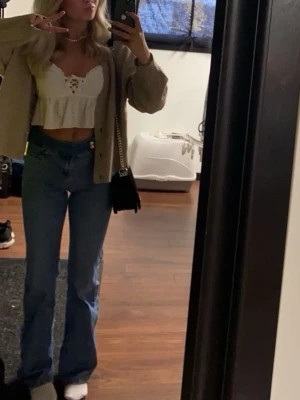 Blå bootcut jeans med hög midja - Säljer ett par blå midwaste bootcut jeans. Jeansen har en knappdetalj i midjan och är tillverkade i ett stretchigt denimtyg 