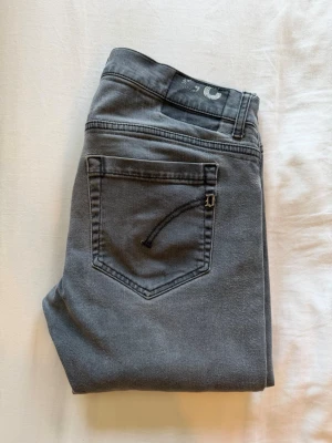 Dondup george jeans - Snygga gråa skinny jeans med klassiska bakfickor och smal passform. Jeansen har en enkel design utan slitningar och är tillverkade i ett stretchigt material som sitter tajt längs benen. Perfekta för en clean och stilren look.