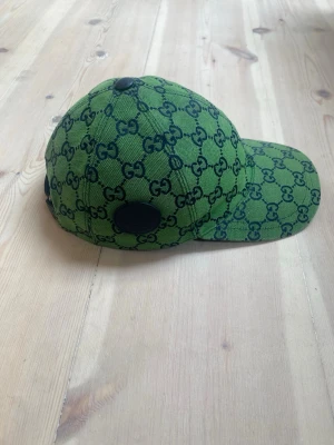 (Äkta) Gucci GG Multicolor Keps Grön/Mörkblå - Mycket sällsynt keps! Gucci GG Multicolour-keps från den limiterade capsule collection-kollektionen från 2021.   Grön canvas med marinblått GG-monogram och marinblå läderdetalj på sidan.   Storlek S (57 cm), justerbar passform.  Väldigt fint skick, knappt använd.  Se bilder för detaljer.