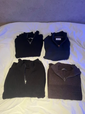 Fyra stickade halvzip-tröjor - Fyra stycken half-zip tröjor i fint skick, den ena blåa är från Zara och den andra från pier one. Den bruna är från dressman och den svarta från lager 157, alla tröjor går för olika mycket så kom med bud, vissa är i nyskick medans andra i använt men fortfarande bra skick.