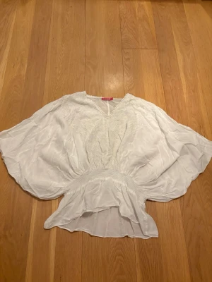 Vit blus med vida ärmar - Säljer en jätte fin vit blus med v-ringning och broderade detaljer. Blusen har vida, fladdriga ärmar och markerad midja med resår. Säljer då den tyvärr är för stor för mig, köpt second hand!