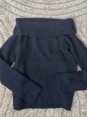 Mörkblå off shoulder stickad tröja - Mysig mörkblå stickad tröja från Gina Tricot med bred off shoulder-krage och långa ärmar. Tröjan har ribbstickade muddar vid ärmslut och nederkant, perfekt för kalla dagar. Materialet känns mjukt och värmande.