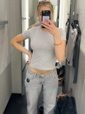 Grå croppad t-shirt från Intimissimi - Säljer en ljusgrå croppad t-shirt från Intimissimi i mjuk Supima-bomull. T-shirten har rund halsringning och korta ärmar, perfekt för en clean och enkel look. Passformen är tight och materialet känns riktigt skönt mot huden.