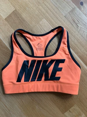 Orange sport-bh från Nike - Säljer en sportig orange sport-bh från Nike med svart logga framtill och svarta kantband. Ej vadderade kupor. Perfekt för träning och aktiva dagar 👟⭐️superfint skick, nästan som ny, använd fåtal tillfällen. 