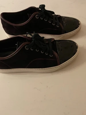 Lanvin skor Storlek 42 - Snygga och stilrena Lanvin sneakers i vinrött, med exklusiv design och lackad tå.  👟 Storlek: 42 🍷 Färg: Vinröd 📦 Skick: Bra begagnat skick. Det finns några mindre defekter/slitage på den lackade tån, vilket syns på bilderna. 💰 Pris: 1 800 kr  Säljes då de inte kommer till användning. Skicka gärna meddelande vid intresse!