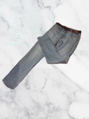 Levis 511 Jeans - Säljer ett par ljusblå jeans med rak passform och klassisk femficksdesign. Jeansen har en brun skinnpatch i midjan och subtila slitningar för en avslappnad look. Tillverkade i denim med en vintagekänsla. W30 L32