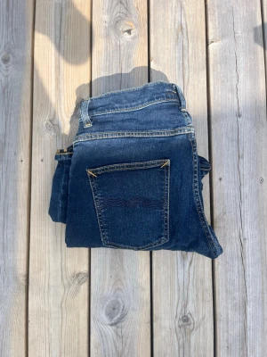 Nudie jeans  - Snygga mörkblå jeans från nudie. Storlek W31 L32. Perfekt nu till det kalla vädret 🍁. Litet hål i skrevet innan men som sedan lagades av nudie själva. 