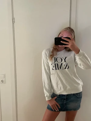 Vit sweatshirt med tryck - Vit sweatshirt med svart texttryck på bröstet. Tröjan har rund halsringning och långa ärmar. Tillverkad i mjukt material som ger en avslappnad look. Passar perfekt till jeans eller kjol för en casual stil.