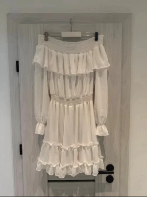 Vit offshoulder volangklänning - En jättefin och somrig miniklänning från Bik Bok Perfekt för varma sommardagar, studenten, midsommar eller festen Märke: Bik Bok Storlek: S. Material: 100% Polyester. Ärmarna är lite genomskinliga, medan kjolen har ett praktiskt underkjolsfoder. Skick: köptes från vinted(ny utan prislapp), själv har jag aldrig använt den.  🏠Kommer från ett rök-och djurfritt hem. Fraktar samma dag! Hör av dig om du har några frågor eller vill ha fler bilder säljer av flera plagg just nu!🤍