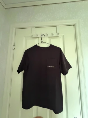Svart t-shirt med bröstficka - En stilren svart t-shirt med rund hals och bröstficka. På fickan finns en liten broderad textdetalj. Perfekt basplagg till garderoben och passar till det mesta. Tillverkad i mjuk bomull för skön känsla. Pris kan diskuteras 