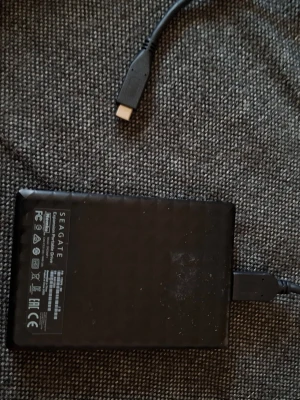 Extern hårddisk Seagate svart USB - Säljer en extern hårddisk från Seagate i svart plast med diskret mönstrad yta. Kommer med USB-kabel för enkel anslutning till dator eller laptop. Perfekt för extra lagring av filer, bilder och filmer.