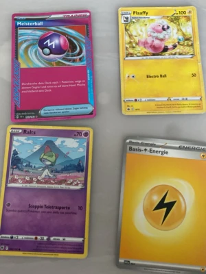 Fyra Pokémonkort blandade typer - Säljer fyra olika Pokémonkort: Meisterball (tränarkort), Flaaffy (gul bakgrund), Ralts (lila bakgrund) och ett Basis-Energie kort (gul). Perfekt för samlare eller dig som vill bygga din egen lek. Alla kort har färgstarka illustrationer och klassisk Pokémon-design.