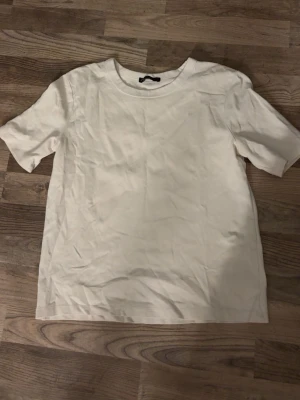 Vit basic t-shirt i bomull - En enkel och stilren vit t-shirt med rund hals och korta ärmar. Perfekt att matcha med jeans eller shorts för en clean look. Tillverkad i mjuk bomull för skön komfort.